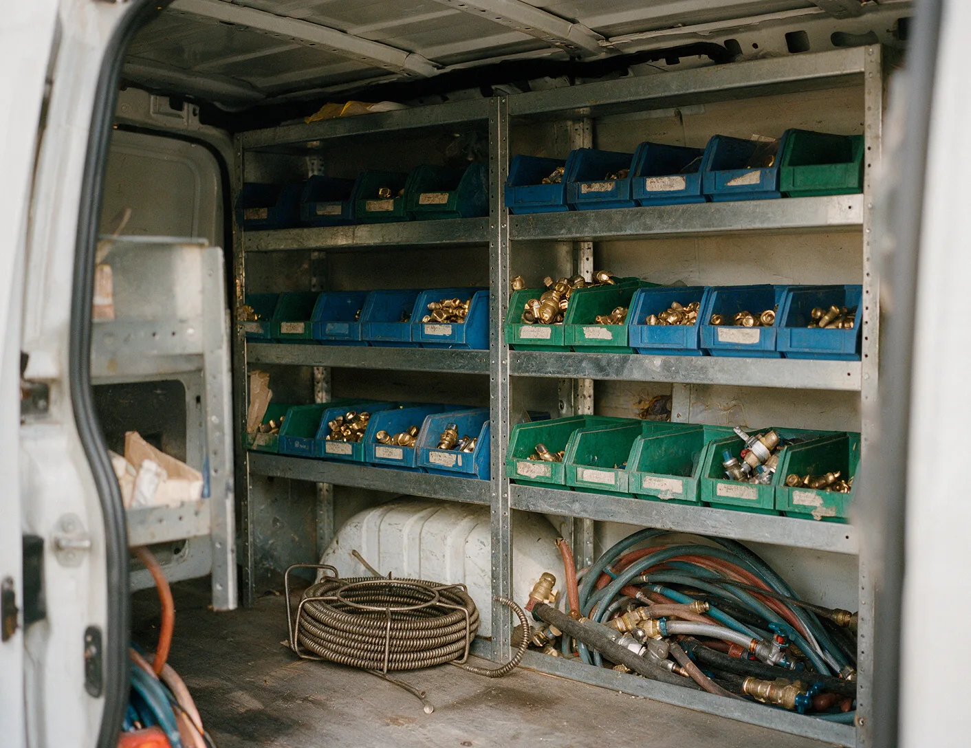 Organized plumbing parts bins on work van shelving